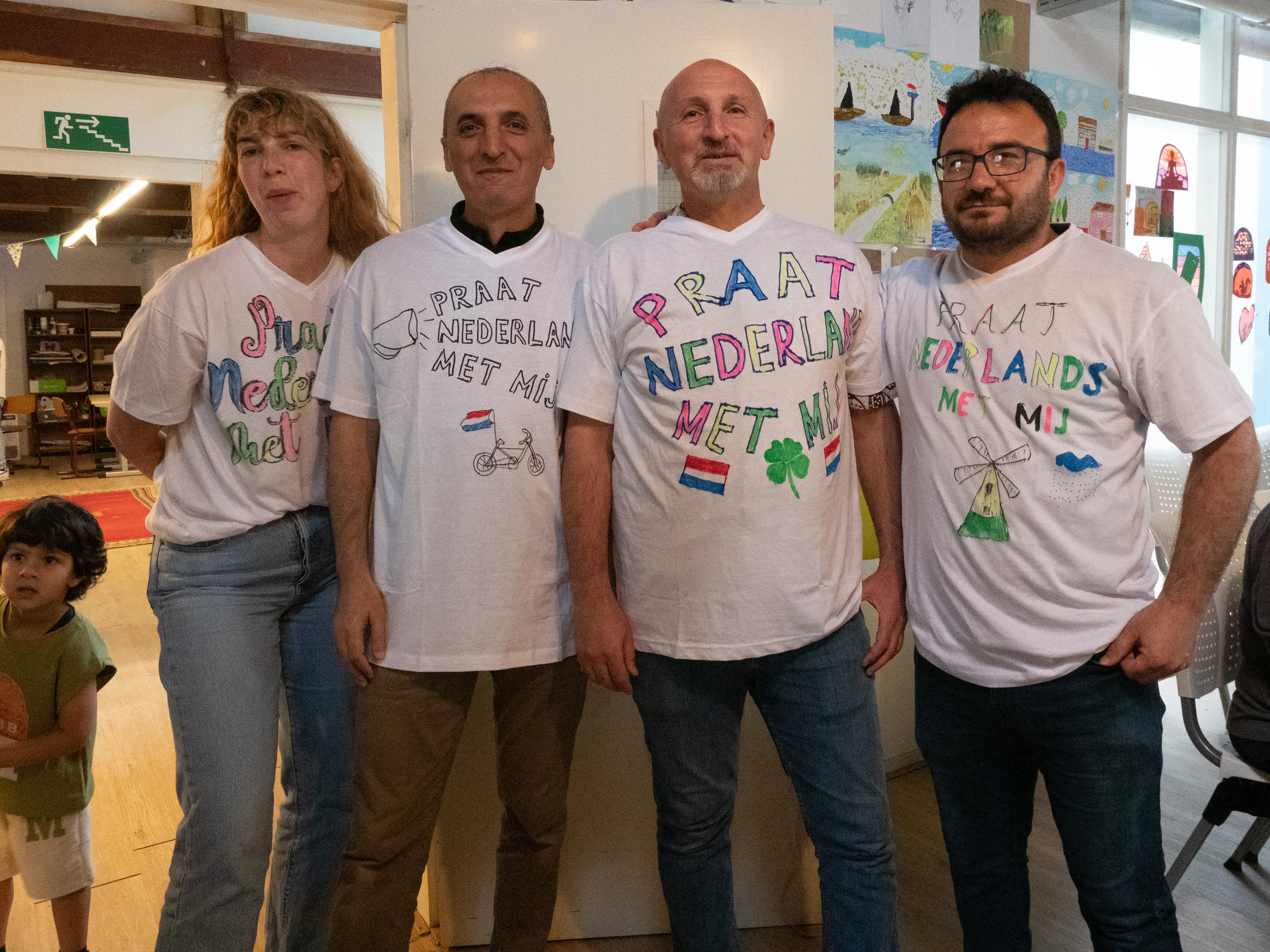 Drie mannen en de docent lten hun T-shirt zien